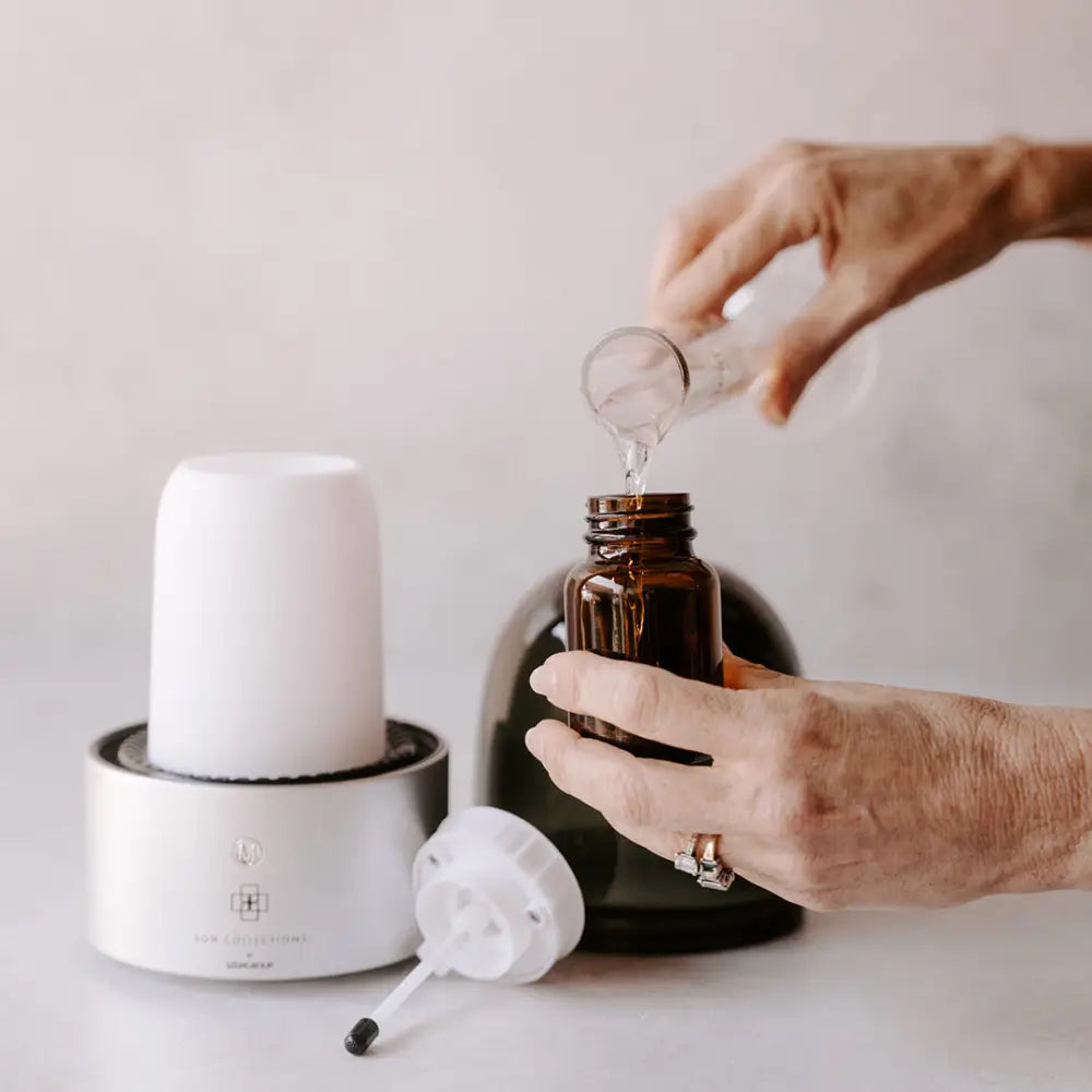 Person pouring liquid into Roma Elegance Electric aroma diffuser with LED lighting and cold air diffusion